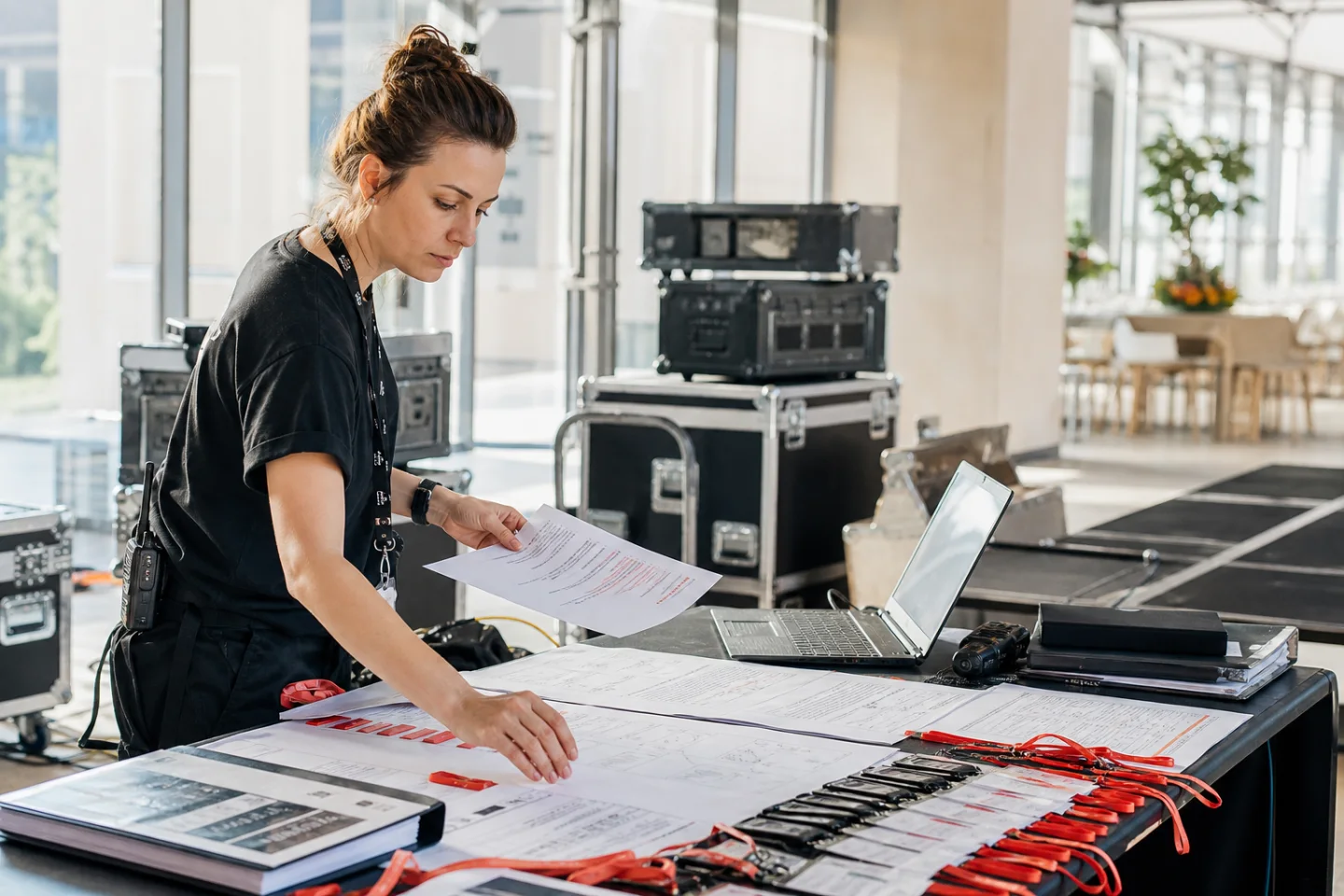 Production coordinator organising event documents and credentials at a venue
