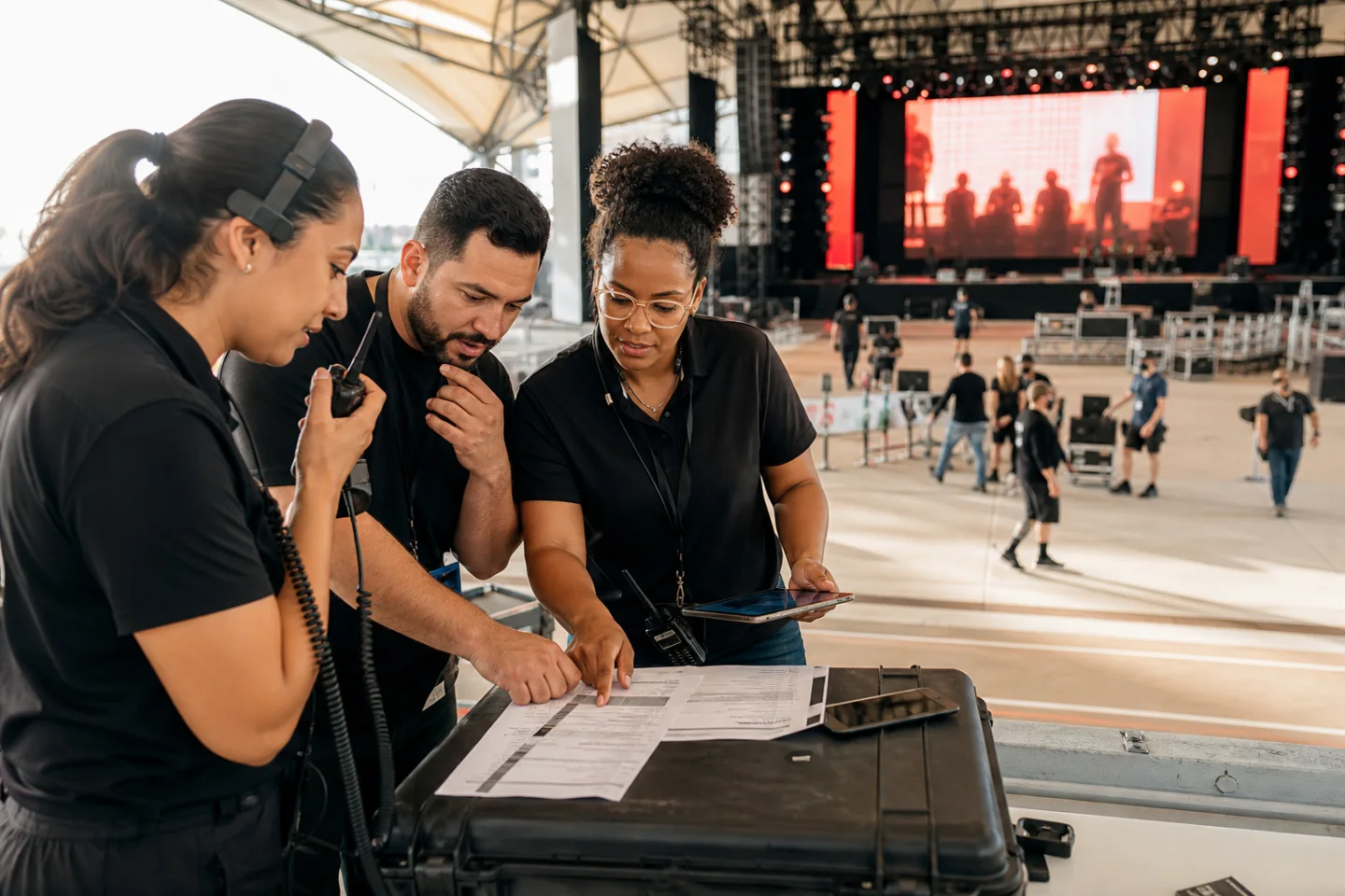 Live event operations team coordinating over a run sheet and tablet at a venue
